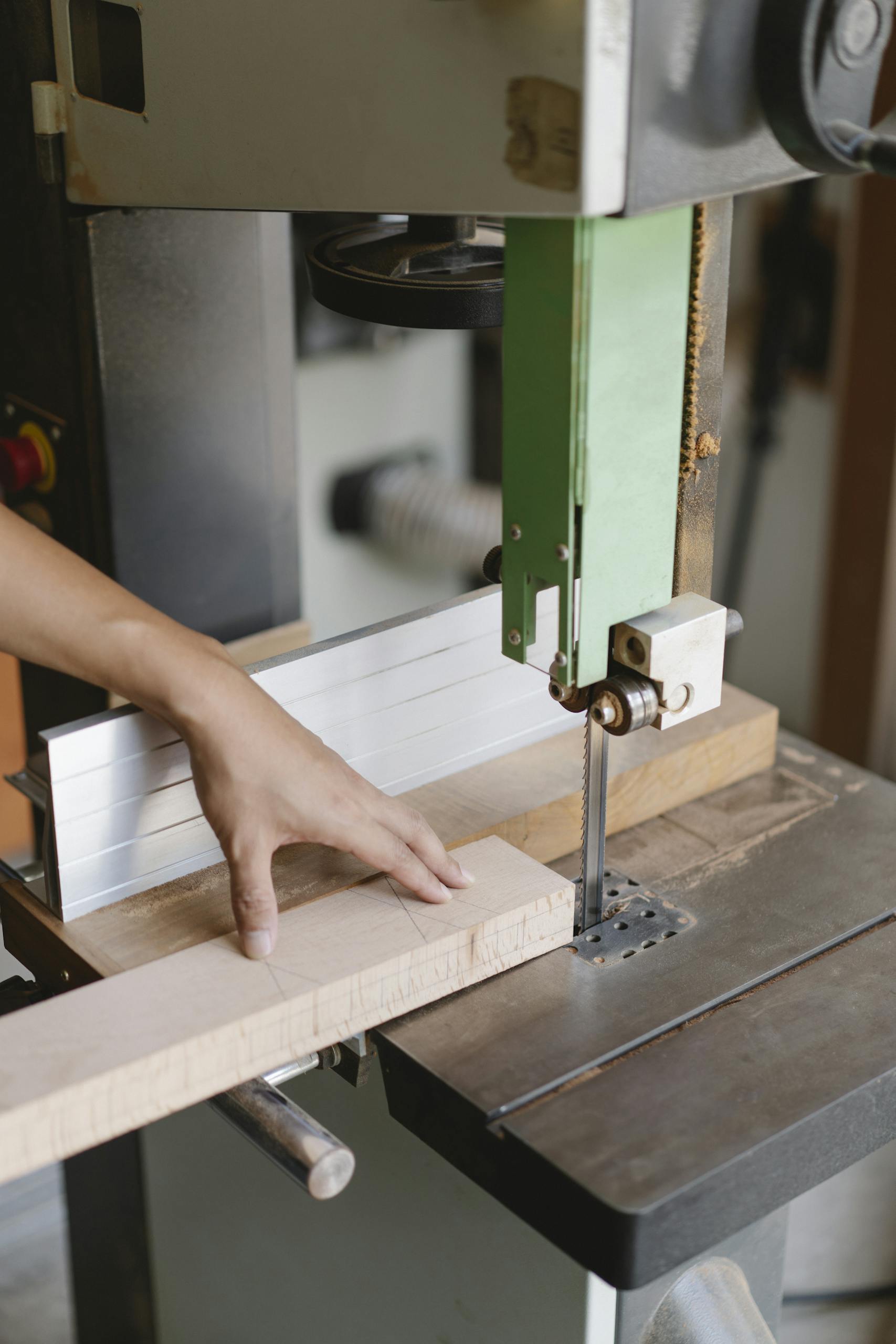 Crop unrecognizable woodworker sawing wooden plank with band saw with sharp blade in daytime