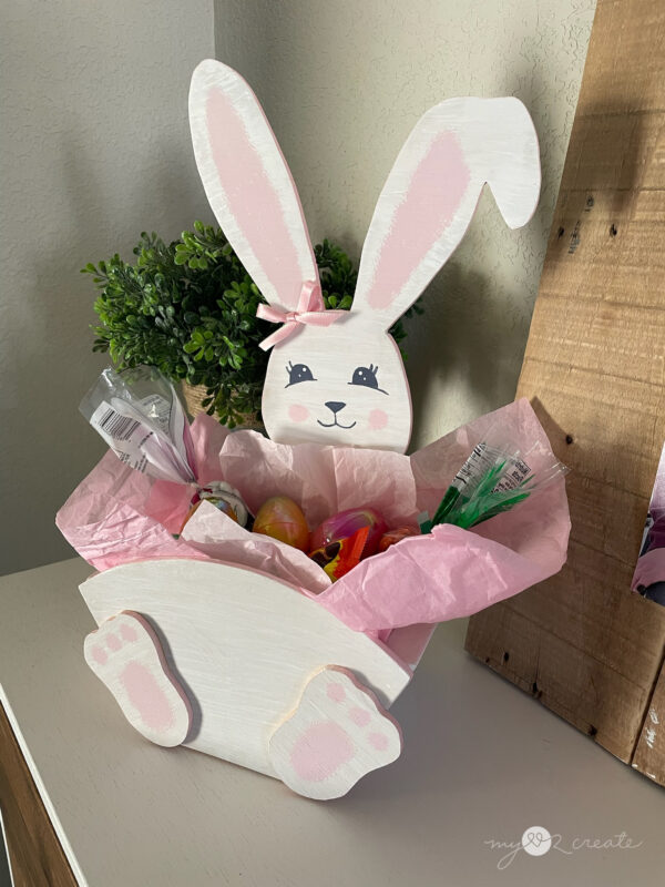 Handmade wooden Easter Bunny crate filled with Easter treats, decorated with a painted bunny face and pink ribbon bow.