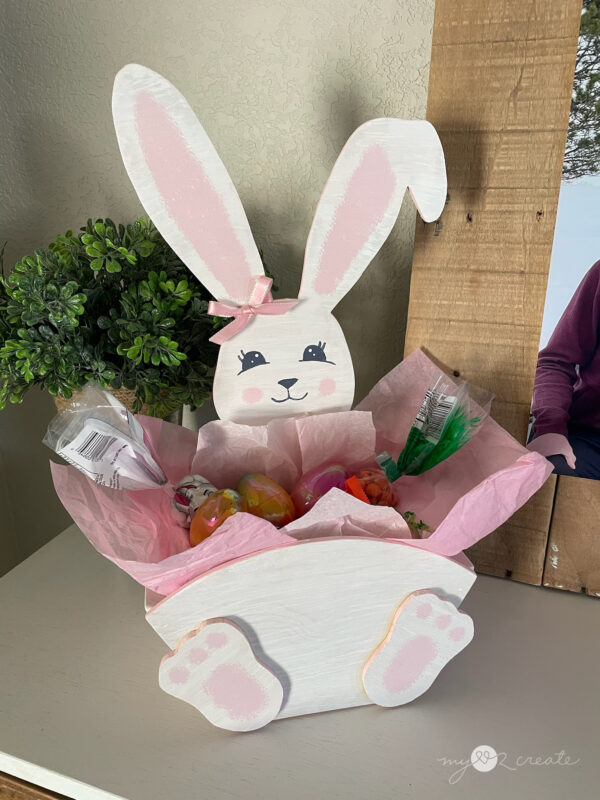 Handmade wooden Easter Bunny crate filled with Easter treats, decorated with a painted bunny face and pink ribbon bow.