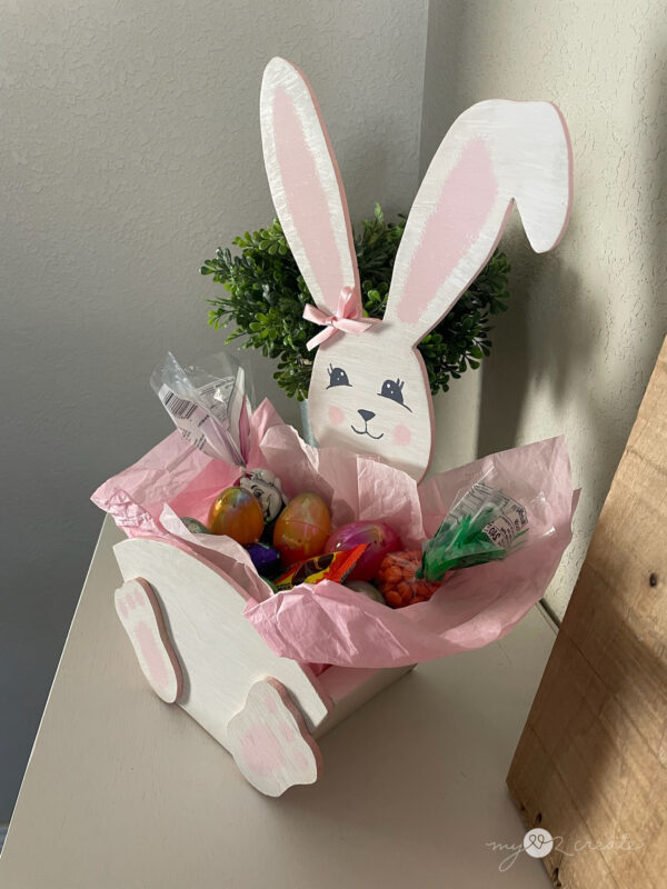 Handmade wooden Easter Bunny crate filled with Easter treats, decorated with a painted bunny face and pink ribbon bow.